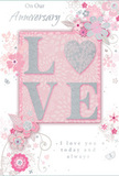 In this image, an anniversary card is shown in close detail, its design a soft celebration of enduring romance that would feel perfectly at home in a quiet corner café off Goldhawk Road. The focal point is the word LOVE, set proudly across the middle of the card in large, raised letters. These letters are cloaked in an even layer of soft glitter, blending pastel pinks with silvery whites, and edged so finely that the word glows without appearing garish. The letter O is transformed into a shimmering heart, its surface slightly more textured and infused with silver tones, making it look like a tiny keepsake charm embedded into the card. Around this central word, clusters of delicate blooms unfurl with watercolor softness-blush and mauve petals melting gently into the pale pink background. Their outlines are defined by flowing lines in muted grey and silver, evoking the graceful curves of stems arranged in a romantic bouquet. Small swirls, loose petals, and understated butterflies seem to drift through the space, adding a sense of motion akin to a breeze through a spring garden near Shepherd's Bush Common. The background remains a serene, dusty pink, creating a feeling of warmth and intimacy that highlights the floral details without distraction. The phrases On Our Anniversary and I love you today and always appear in a refined, flowing script, printed in calm grey ink that harmonizes with the silvery touches around the flowers. Every element-from the tactile glitter to the fine linework-contributes to a mood of quiet devotion, as if the card itself were a keepsake bouquet pressed flat, capturing years of shared memories in a single, tender gesture.
